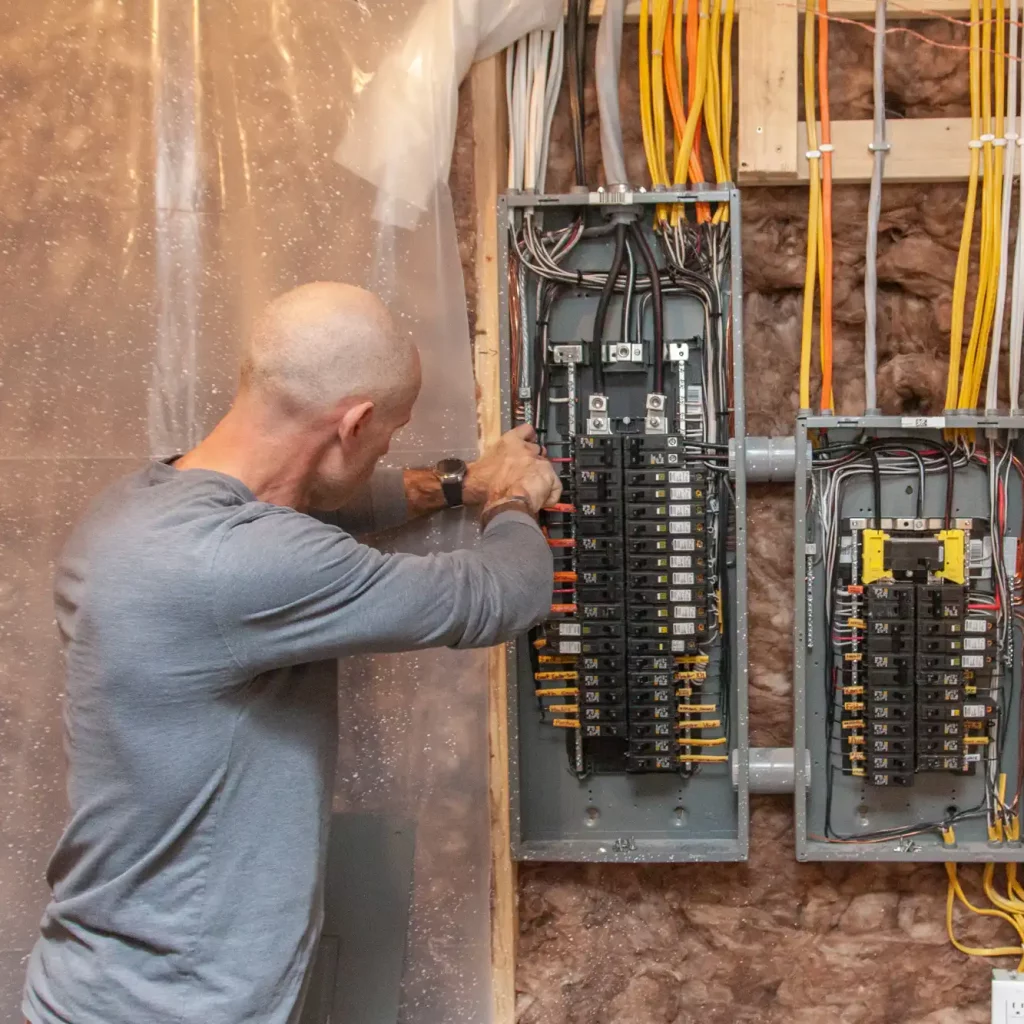 Electrician working on an interior breaker panel upgrade in a residential home.